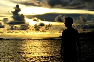 Silhouette man standing by sea against sky during sunset