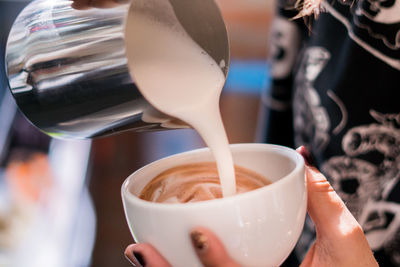 Close-up of hand pouring coffee in cup