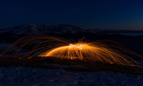 Light trails on field against sky at night