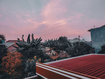 Trees and buildings against sky during sunset