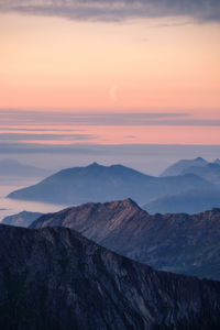 Scenic view of mountains and moon against sky during sunset