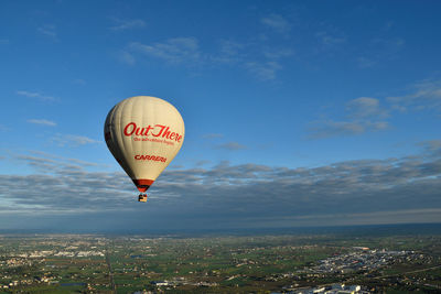 Hot air balloons flying in city against sky