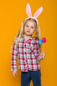 Portrait of cute girl standing against yellow background