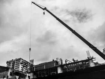 Low angle view of crane in building against sky