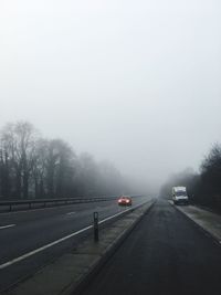 Cars on road against sky during rainy season