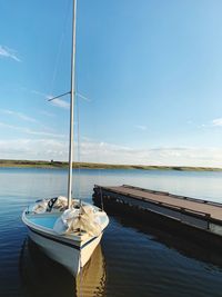 Sailboats moored on sea against sky