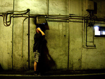 Side view of man standing by wall at night