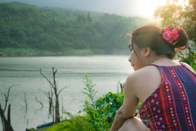 Rear view of young woman standing against sea