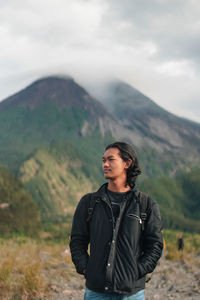 Young man standing on mountain against sky