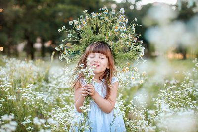 Beautiful young woman with pink flower against plants