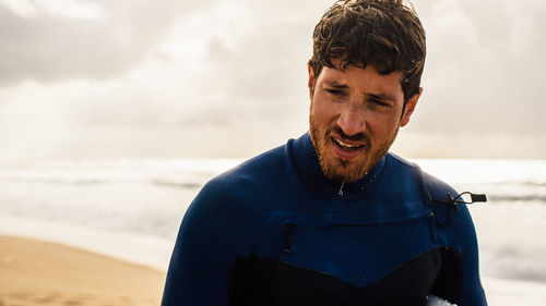 Close-up of young exhausted surfer on beach