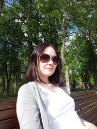 Portrait of young woman wearing sunglasses against trees