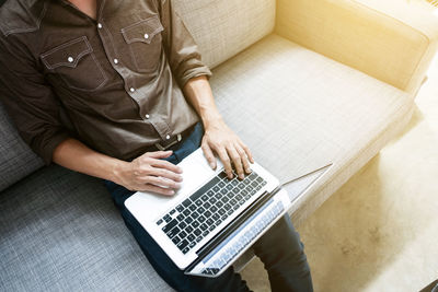 High angle view of man using mobile phone while sitting on sofa