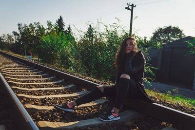 Portrait of woman sitting on railroad track