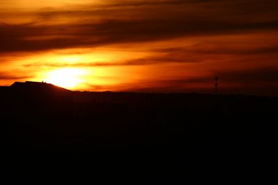Silhouette landscape against dramatic sky during sunset