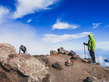 Low angle view of man standing on rock against sky