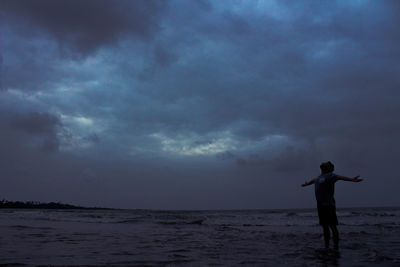 Man standing on beach against sky at night