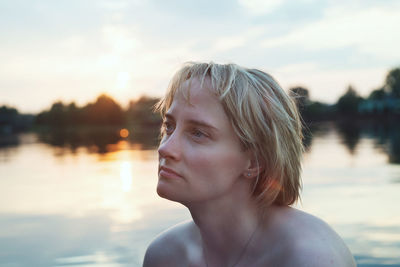 Close-up of thoughtful woman looking away against lake
