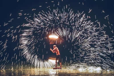 Man spinning wire wool while standing outdoors at night