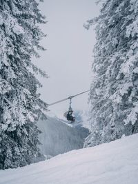 Low angle view of people on ski lift over snowcapped mountain against sky