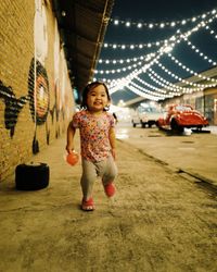 Full length portrait of cute baby girl walking on footpath at night