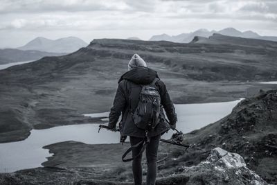 Rear view of hiker standing on hill against river