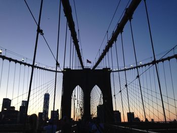 People on brooklyn bridge in city during sunset