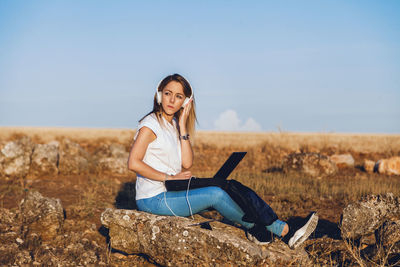 Portrait of smiling young woman sitting on land