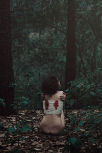 Rear view of woman standing in forest