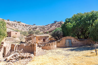 Old houses by mountains against clear sky during sunny day