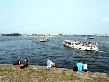 People on boat sailing in river against sky