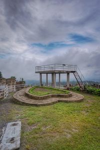 Built structure on field against cloudy sky