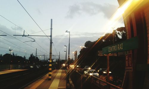 Vehicles on illuminated road against sky at dusk