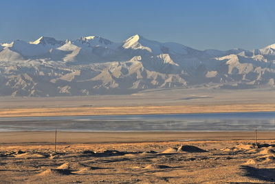 Scenic view of snowcapped mountains by sea against sky