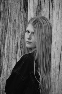 Close-up portrait of young woman against wooden posts