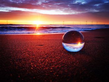 Glass on beach against sky during sunset