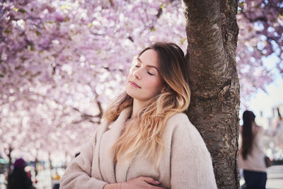 Young woman standing under cherry blossom