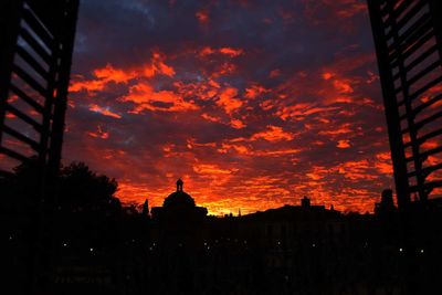 Silhouette of building against cloudy sky at sunset