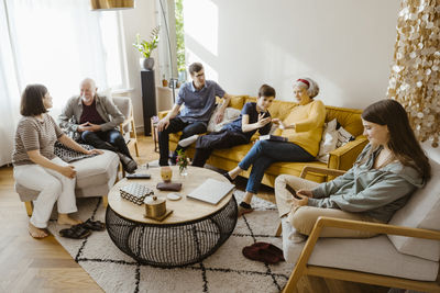 Multi-generation family using wireless technologies and talking while sitting in living room at home
