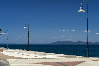 Street light by sea against clear blue sky