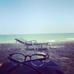 Deck chairs on beach against clear sky