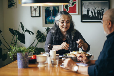 Happy senior woman having salad with man at table