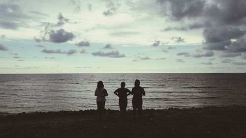 Silhouette people standing on beach against sky during sunset