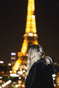 Woman looking at illuminated eiffel tower