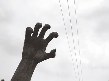 Low angle view of hand statue against sky