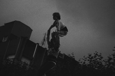 Low angle view of man holding umbrella against sky