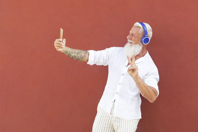 Side view of man standing against red background