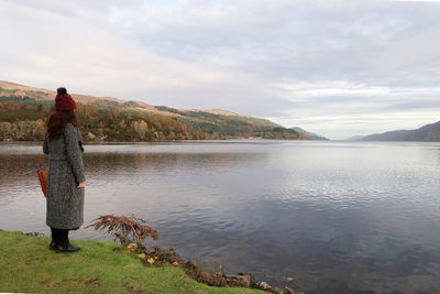 Rear view of woman standing against lake