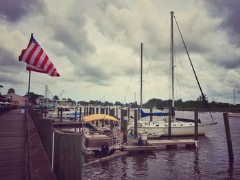 Sailboats moored at harbor against sky