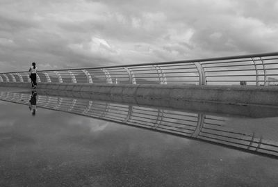 Man walking on bridge over river against sky